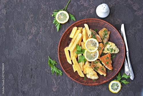 Fried perch fillet with fries on a brown clay plate. Top view, copy space
