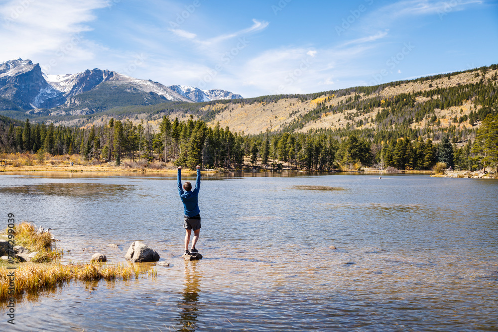 Rocky Mountain National Park, Colorado, USA: A man standing on a rock at Spraque Lake with his arms in the air. Rocky Mountain National Park, Colorado, USA: A man standing on a rock at Spraque Lake with his arms in the air.