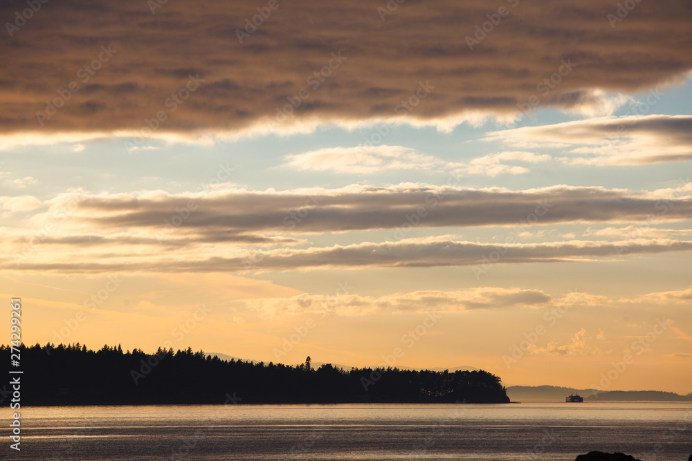 Sunset and distant ferry as seen from the south cove on Jones Island in the San Juan Isands of northwest Washington State. The island is a 188 acre State Park that is only accessible by boat and has 24 campsites. Sunset and distant ferry as seen from the south cove on Jones Island in the San Juan Isands of northwest Washington State. The island is a 188 acre State Park that is only accessible by boat and has 24 campsites.