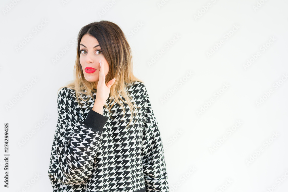 Young woman wearing casual sweater over isolated background hand on mouth telling secret rumor, whispering malicious talk conversation Young woman wearing casual sweater over isolated background hand on mouth telling secret rumor, whispering malicious talk conversation