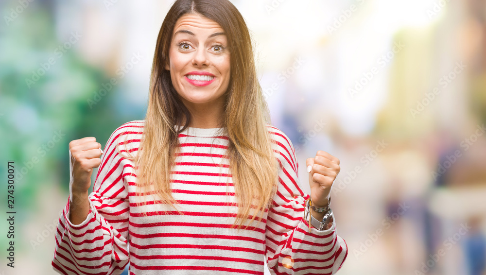 Young beautiful woman casual stripes winter sweater over isolated background celebrating surprised and amazed for success with arms raised and open eyes. Winner concept. Young beautiful woman casual stripes winter sweater over isolated background celebrating surprised and amazed for success with arms raised and open eyes. Winner concept.