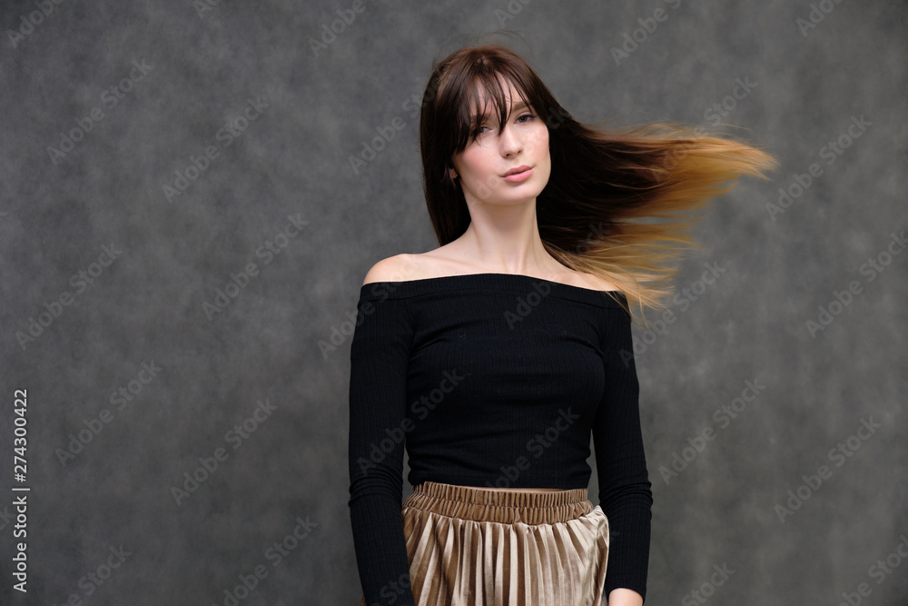 Photo portrait of a beautiful pretty brunette girl in a black sweater on a gray background. A woman is satisfied with her life, she stands in front of the camera, smiling and talking. Made in studio. Photo portrait of a beautiful pretty brunette girl in a black sweater on a gray background. A woman is satisfied with her life, she stands in front of the camera, smiling and talking. Made in studio.