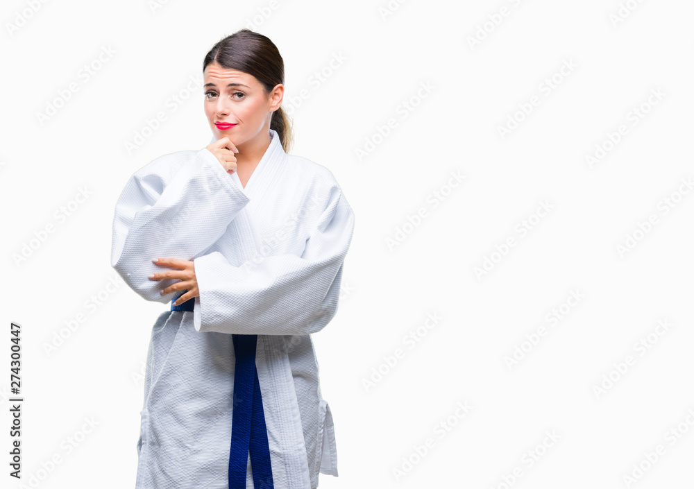 Young beautiful woman wearing karate kimono uniform over isolated background looking confident at the camera with smile with crossed arms and hand raised on chin. Thinking positive. Young beautiful woman wearing karate kimono uniform over isolated background looking confident at the camera with smile with crossed arms and hand raised on chin. Thinking positive.