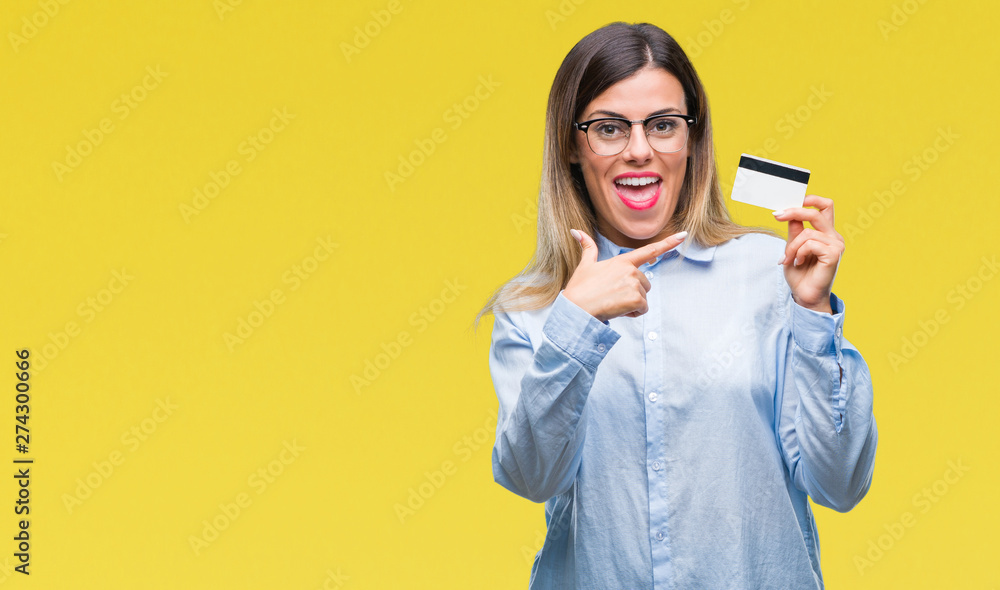 Young beautiful business woman holding credit card over isolated background very happy pointing with hand and finger