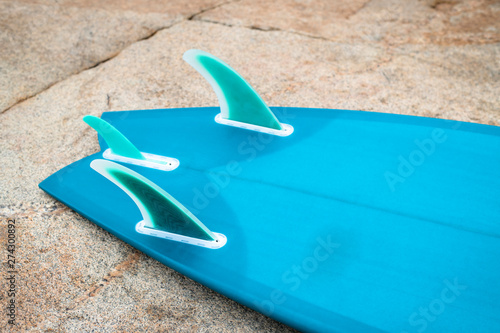 Blue surfboard bottom and fin detail against natural rock texture photo