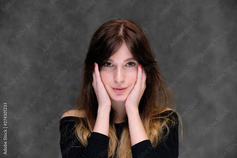 Beauty portrait of a beautiful pretty brunette girl in a black sweater on a dark gray background. A woman is happy with life, she is standing in front of the camera, smiling. Made in a studio. Beauty portrait of a beautiful pretty brunette girl in a black sweater on a dark gray background. A woman is happy with life, she is standing in front of the camera, smiling. Made in a studio.