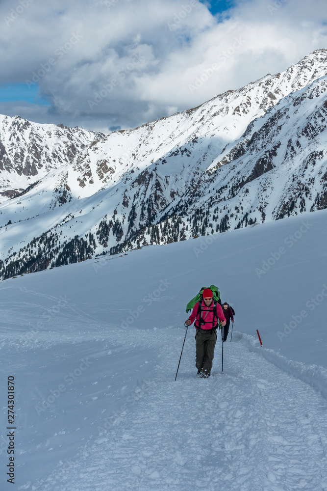Active couple ascending a trail in the snowy Austrian alps Active couple ascending a trail in the snowy Austrian alps