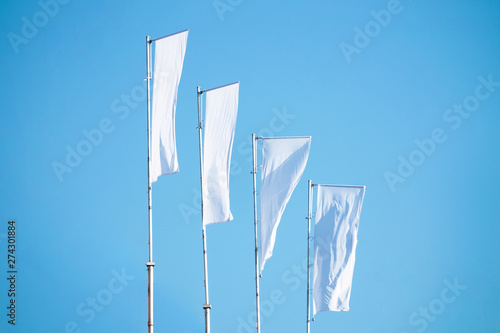 A lot of white flags against the blue sky hanging on the mast, copy space photo