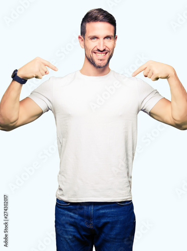 Handsome man wearing casual white t-shirt looking confident with smile on face, pointing oneself with fingers proud and happy. © Krakenimages.com