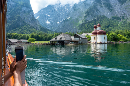 Woman taking a picture of St. Bartholom‰ chapel with her smartphone photo