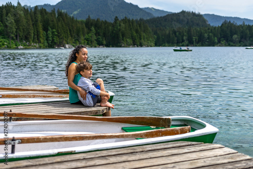 Mother and son sitting on a landing stage at lake Hintersee