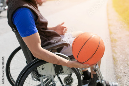 Disabled young basketball player on a wheelchair holding ball and beeing active in sport