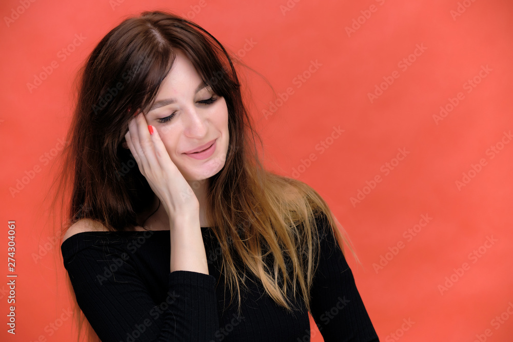 Beauty portrait of a beautiful pretty brunette girl in a black sweater on a red background. A woman is happy with life, she is standing in front of the camera, smiling. Made in a studio. Beauty portrait of a beautiful pretty brunette girl in a black sweater on a red background. A woman is happy with life, she is standing in front of the camera, smiling. Made in a studio.