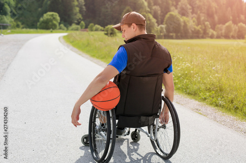 Disabled young basketball player on a wheelchair holding ball and beeing active in sport