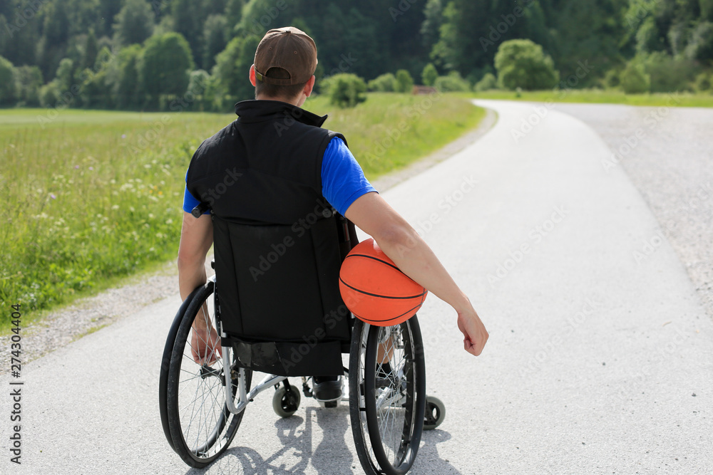 Disabled young basketball player on a wheelchair holding ball and beeing active in sport