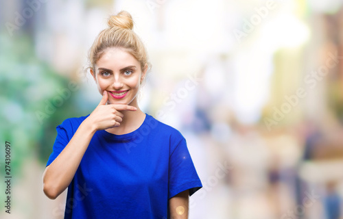Fototapeta Naklejka Na Ścianę i Meble -  Young beautiful blonde and blue eyes woman wearing blue t-shirt over isolated background looking confident at the camera with smile with crossed arms and hand raised on chin. Thinking positive.
