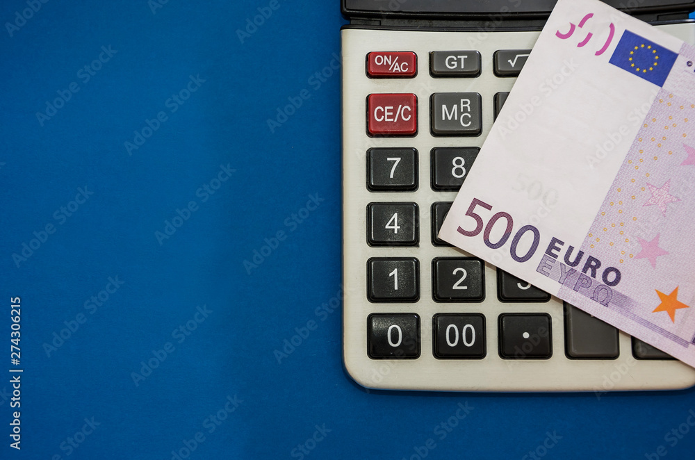 Obraz premium 500 euro banknote on a calculator, close-up, blue background