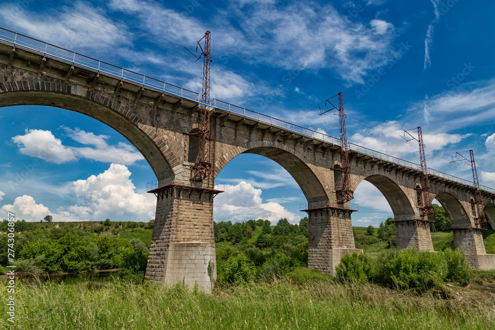 Beautiful old arched stone railway bridge against the backdrop of a scenic landscape