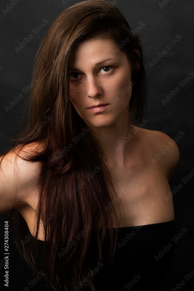 Beautiful woman looking into the camera on black background. Studio shot of fashion attractive female.