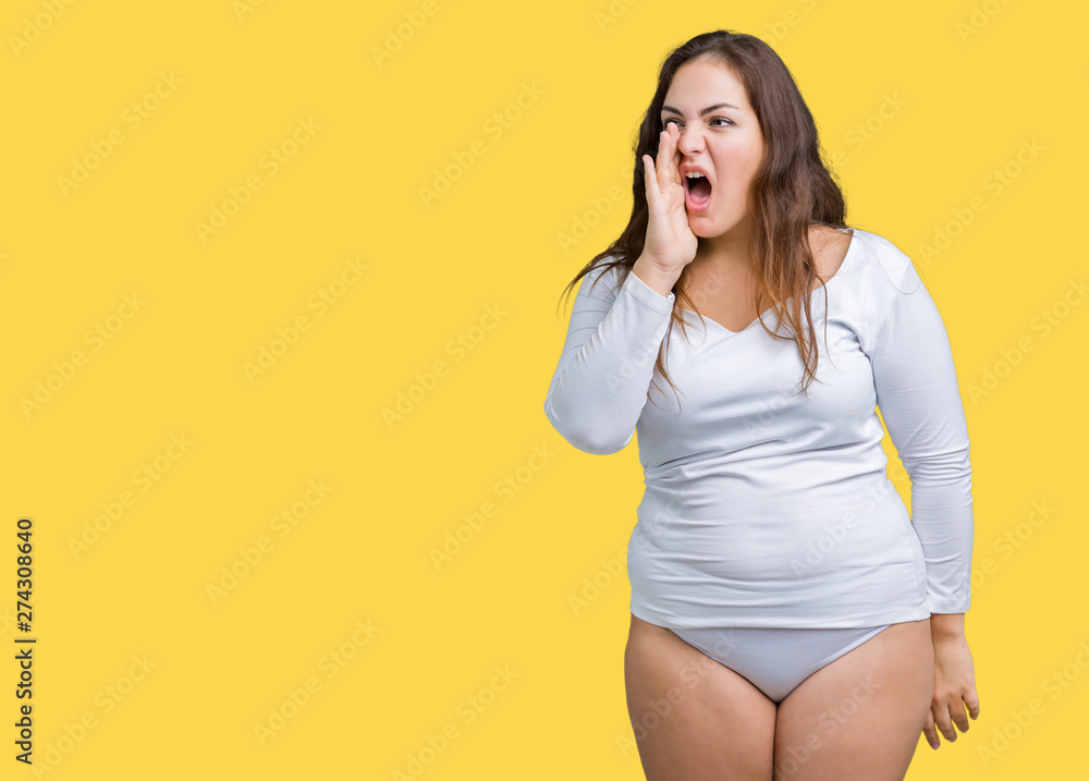 Beautiful plus size young overwight woman wearing white underwear over isolated background shouting and screaming loud to side with hand on mouth. Communication concept.