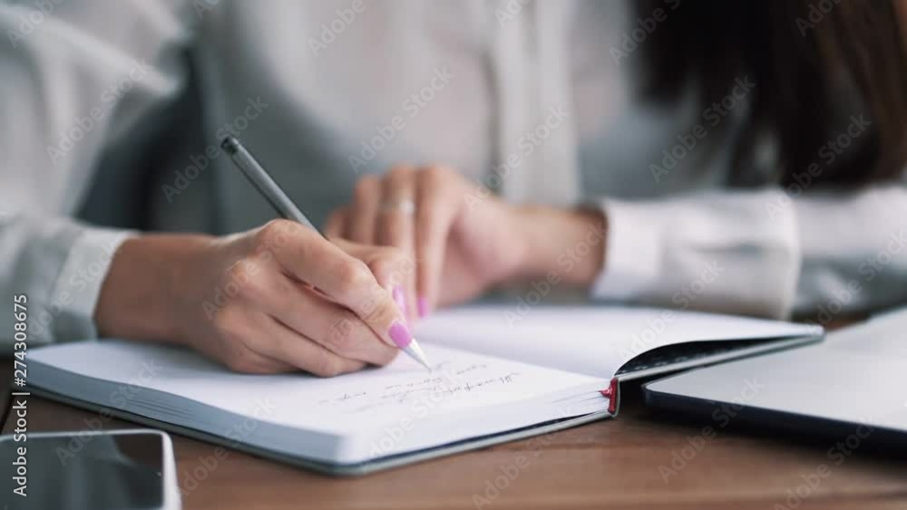 Close up woman hand write notes with pen in notebook, slow motion Close up woman hand write notes with pen in notebook, slow motion