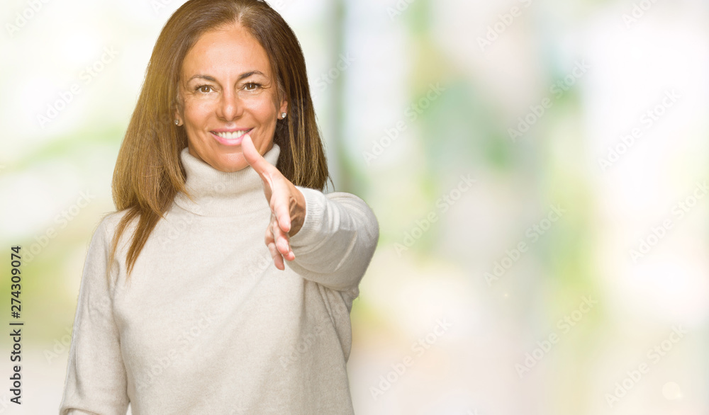 Beautiful middle age adult woman wearing winter sweater over isolated background smiling friendly offering handshake as greeting and welcoming. Successful business. Beautiful middle age adult woman wearing winter sweater over isolated background smiling friendly offering handshake as greeting and welcoming. Successful business.