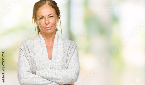 Beautiful middle age adult woman wearing winter sweater over isolated background with serious expression on face. Simple and natural looking at the camera.