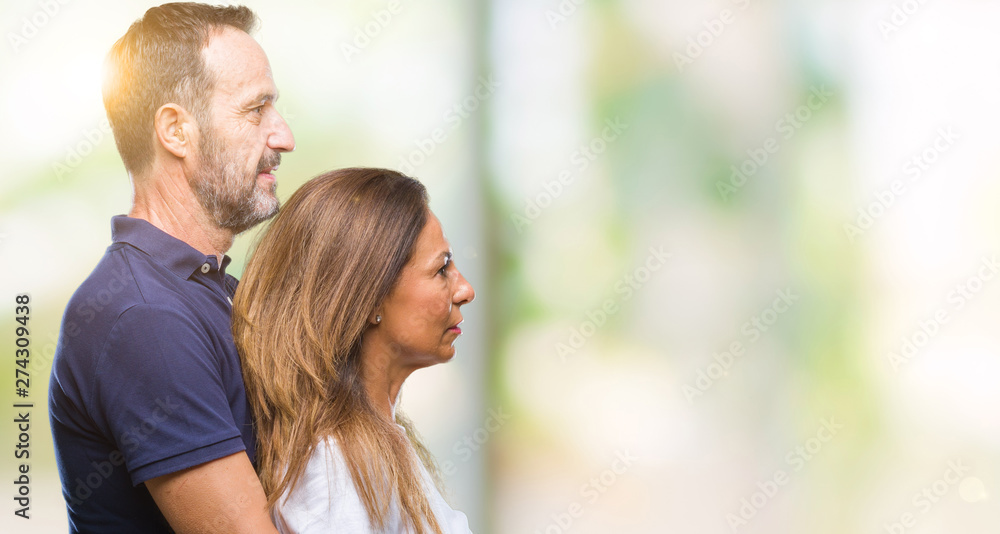Middle age hispanic casual couple over isolated background looking to side, relax profile pose with natural face with confident smile.