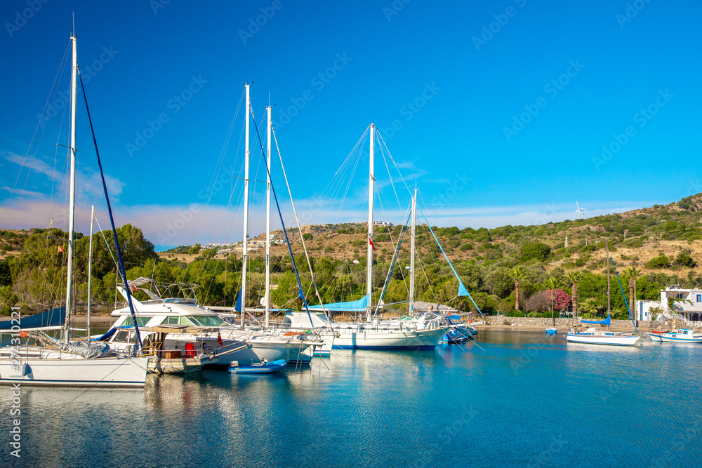 View of the Gumusluk, Bodrum Marina, sailing boats and yachts in Bodrum town, city of Turkey. Shore and coast of Aegean Sea with yachts and boats