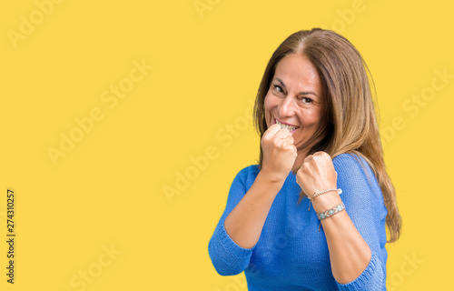 Middle age beautiful woman wearing winter sweater over isolated background Ready to fight with fist defense gesture, angry and upset face, afraid of problem