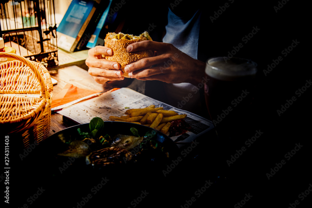A man enjoying a meal with a hamburger and fried chips