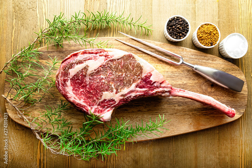 Raw waguy tomahawk steak on wooden background with spices ready forthe bbq photo