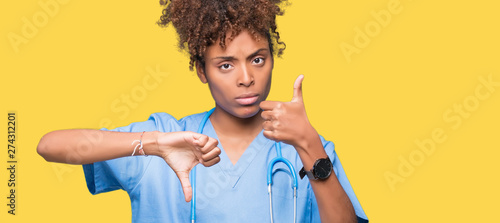 Photos Young african american doctor woman over isolated background Doing thumbs up and down, disagreement and agreement expression