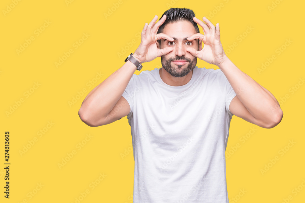 Fototapeta premium Handsome man wearing white t-shirt over yellow isolated background Trying to open eyes with fingers, sleepy and tired for morning fatigue