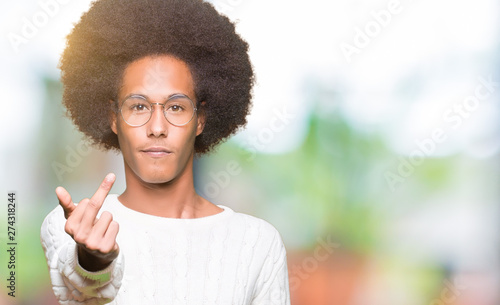 Young african american man with afro hair wearing glasses Showing middle finger, impolite and rude fuck off expression © Krakenimages.com