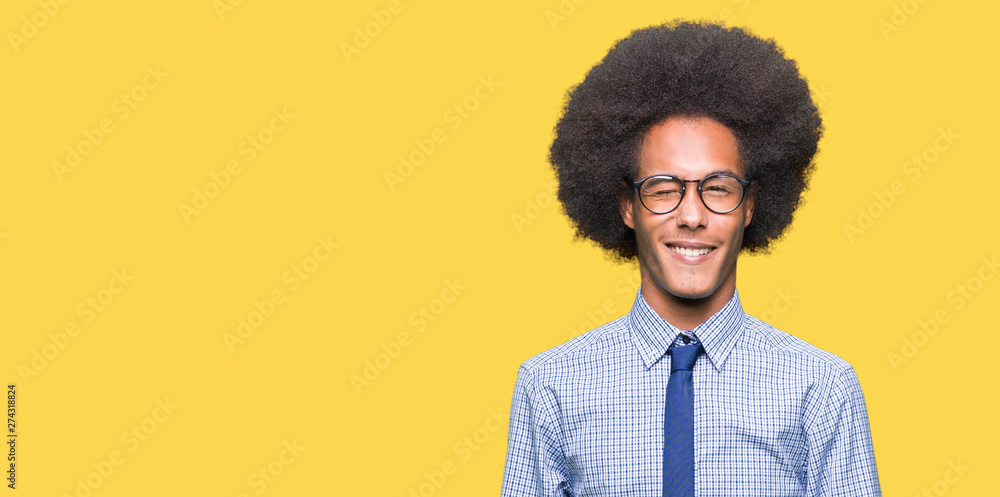 Young african american business man with afro hair wearing glasses winking looking at the camera with sexy expression, cheerful and happy face. Young african american business man with afro hair wearing glasses winking looking at the camera with sexy expression, cheerful and happy face.