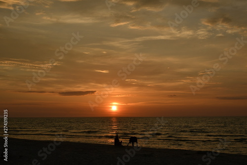 A dog owner at sunset on the beach of Debki