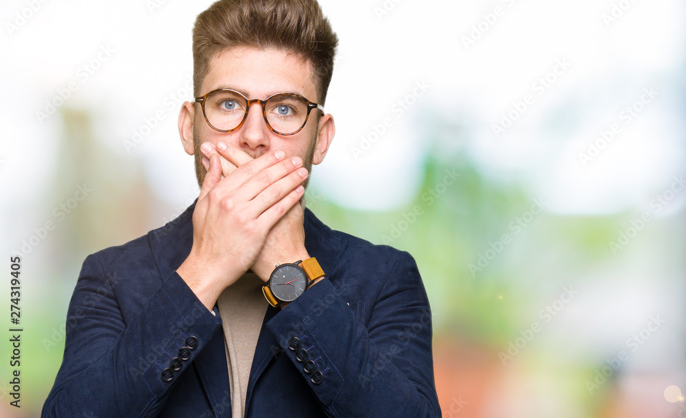Young handsome business man wearing glasses shocked covering mouth with hands for mistake. Secret concept. Young handsome business man wearing glasses shocked covering mouth with hands for mistake. Secret concept.