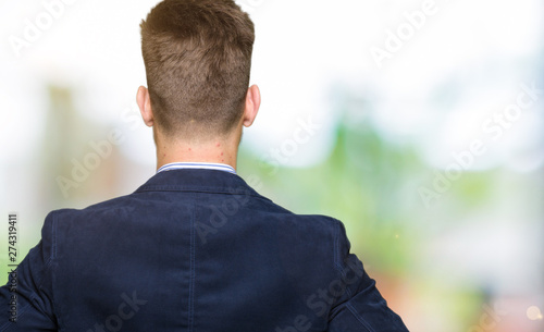 Young handsome bussines man standing backwards looking away with arms on body