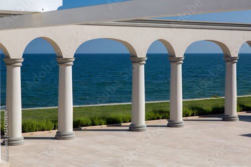 an arch with columns of white stone and a marble floor on sunny day of a luxurious mansion, nobody.