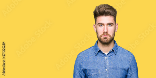 Young handsome blond man wearing casual denim shirt depressed and worry for distress, crying angry and afraid. Sad expression.