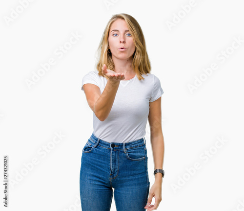 Beautiful young woman wearing casual white t-shirt over isolated background looking at the camera blowing a kiss with hand on air being lovely and sexy. Love expression.