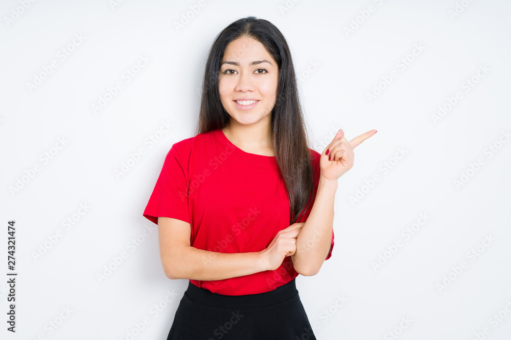 Beautiful brunette woman wearing red t-shirt over isolated background with a big smile on face, pointing with hand and finger to the side looking at the camera. Beautiful brunette woman wearing red t-shirt over isolated background with a big smile on face, pointing with hand and finger to the side looking at the camera.