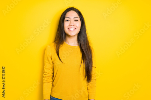 Beautiful brunette woman over yellow isolated background with a happy and cool smile on face. Lucky person.