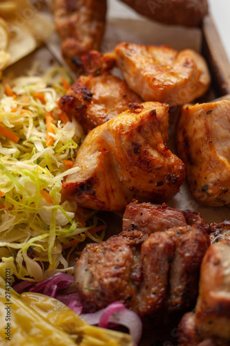 Macro close up of assorted grilled meat snacks: chicken, beef and lamb kebab, roasted pork shish kebab, served with coleslaw