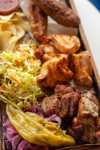 Macro close up of assorted grilled meat snacks: chicken, beef and lamb kebab, roasted pork shish kebab, served with coleslaw