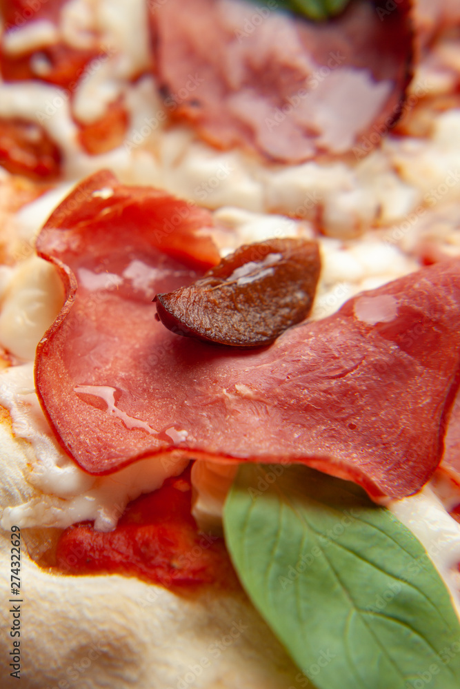 Macro close up of roman square pizza on a thick dough with mozzarella, pastrami, sweet plum and basil leaves, served on a wooden table