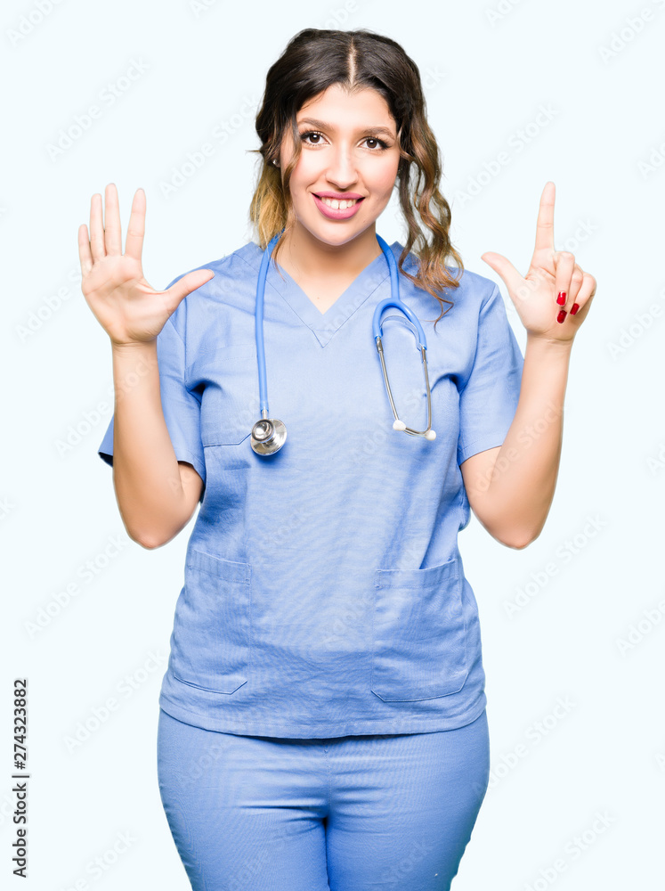 Young adult doctor woman wearing medical uniform showing and pointing up with fingers number seven while smiling confident and happy. Young adult doctor woman wearing medical uniform showing and pointing up with fingers number seven while smiling confident and happy.