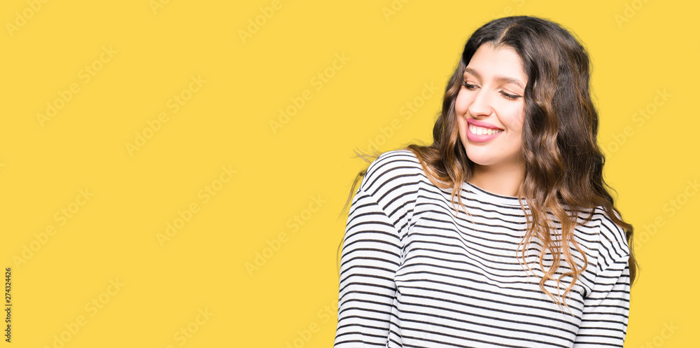 Young beautiful woman wearing stripes sweater looking away to side with smile on face, natural expression. Laughing confident. Young beautiful woman wearing stripes sweater looking away to side with smile on face, natural expression. Laughing confident.