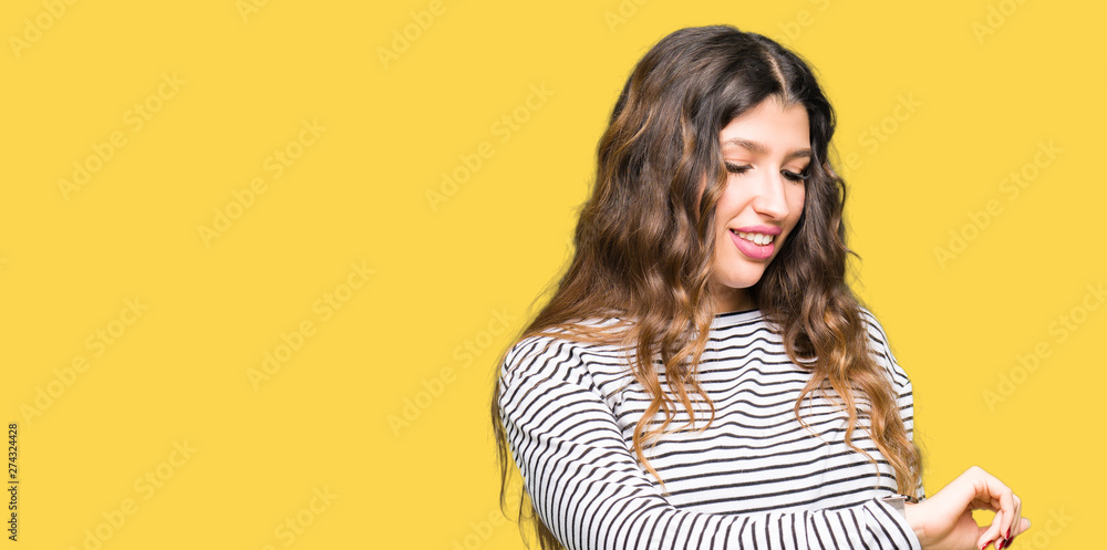 Young beautiful woman wearing stripes sweater Checking the time on wrist watch, relaxed and confident Young beautiful woman wearing stripes sweater Checking the time on wrist watch, relaxed and confident